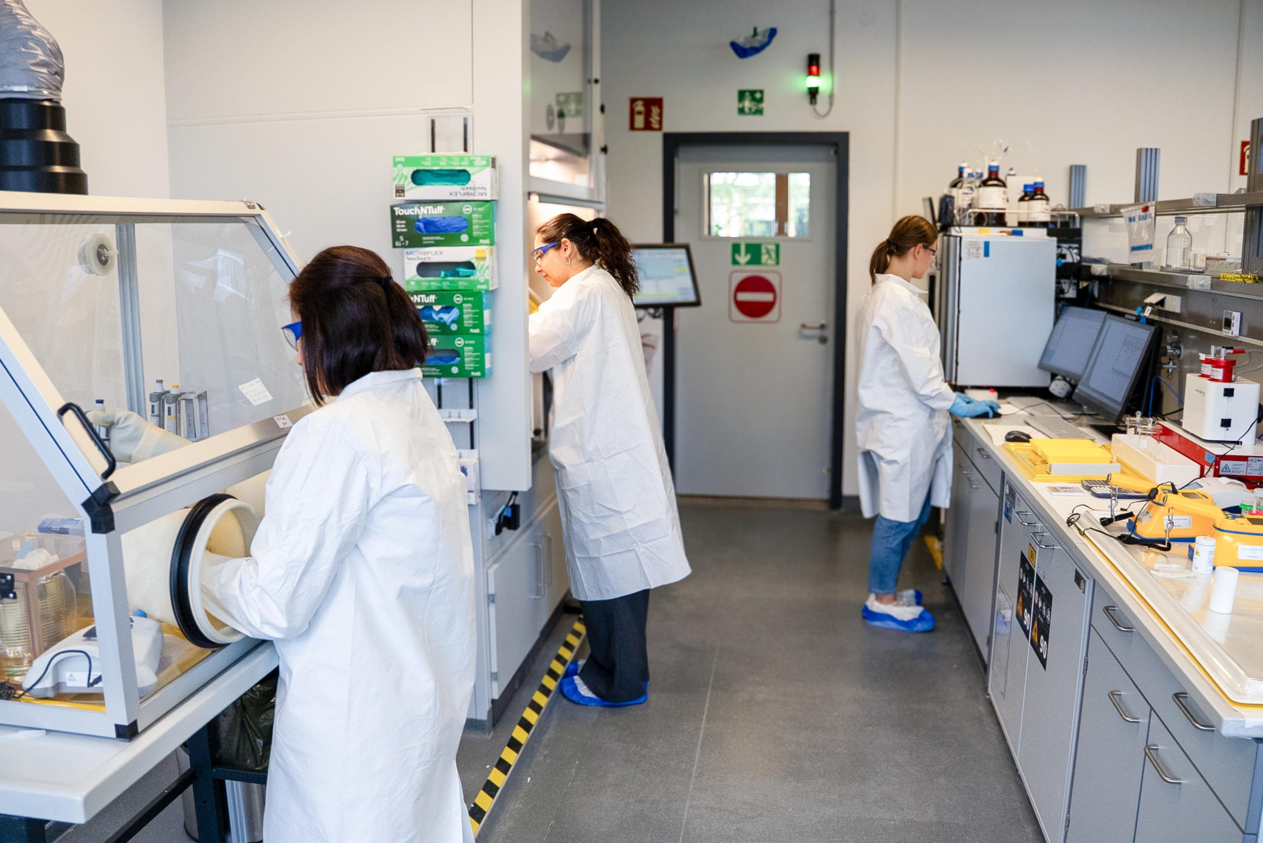 Scientists working in a radiochemistry laboratory setting handling experimental procedures.